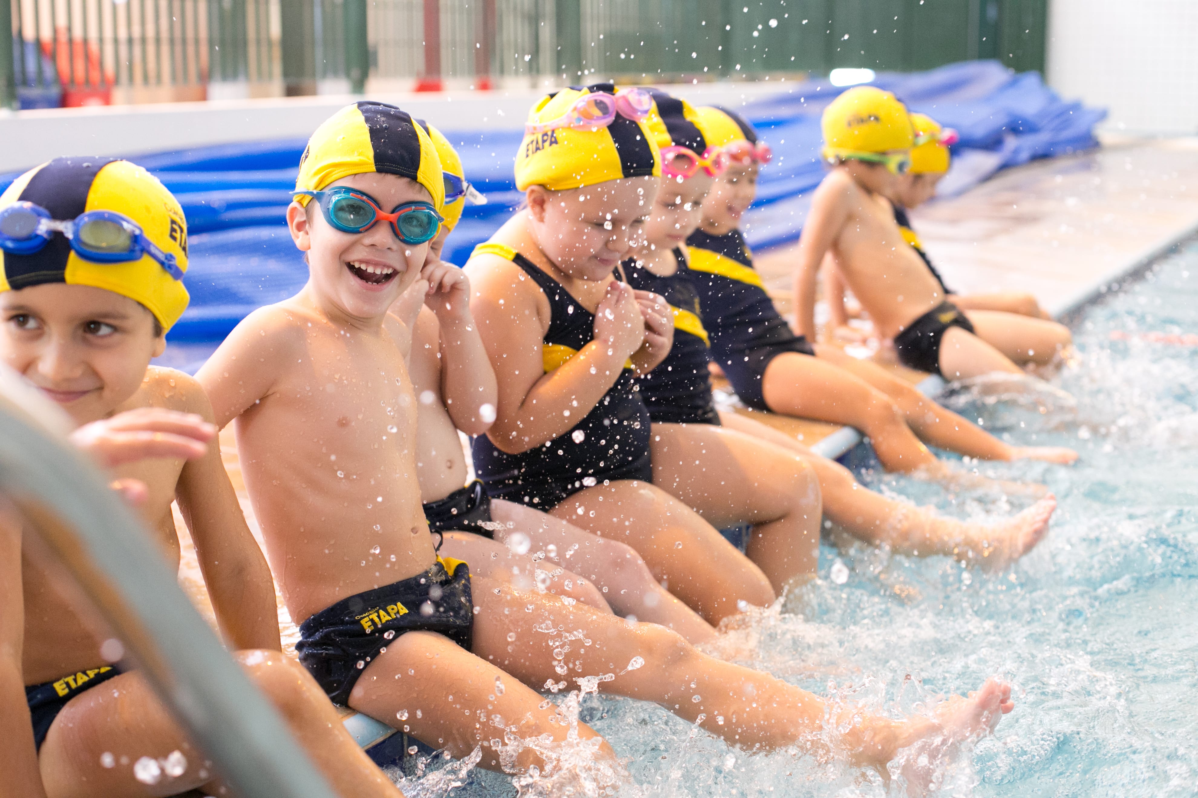 Crianças com uniforme de natação na borda da piscina